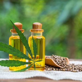 Hemp seeds and hemp oil on wooden table. Hemp seeds in wooden spoon and hemp essential oil in small glass bottle. cannabis oil cbd.